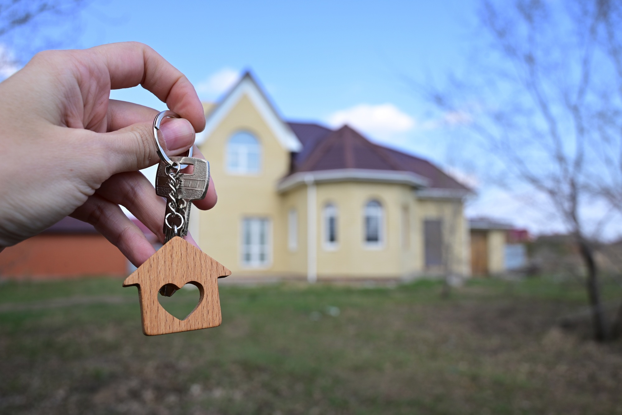 a key with a keychain in the form of a house with a heart on the background of the finished year of