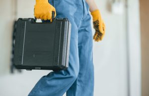 Holding case. Young man working in uniform at construction at daytime